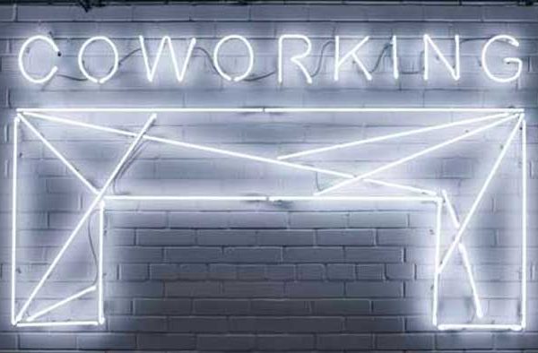 Letrero de neón y fondo de ladrillo con la palabra coworking